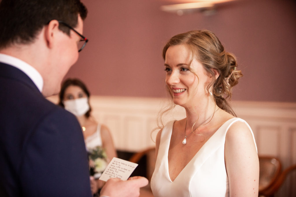 Georgia Aussenac smiling at her husband with tears in her eyes, weaing a white v neck dress.