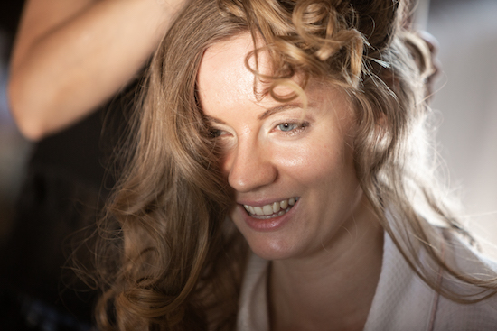 Front view of Georgia getting her hair and makeup done, with blonde curls tumbling over her face and shoulders