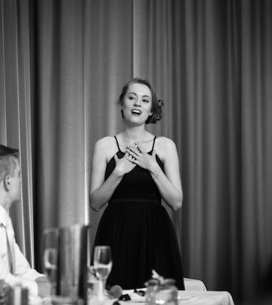 Georgia Aussenac singing at a wedding, with her hands to her chest and a playful look on her face