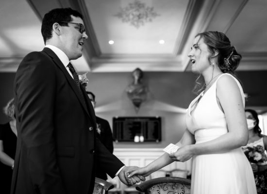 Georgia, a bridge, standing and singing opposite her groom. The photo is in black and white, accentuating her white dress.